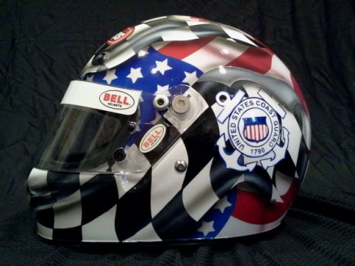 Racing helmet featuring patriotic colors, checkerboard pattern, and sponsor logos.