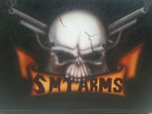 Skull with crossed guns and a banner reading "SMT ARMS" beneath it.