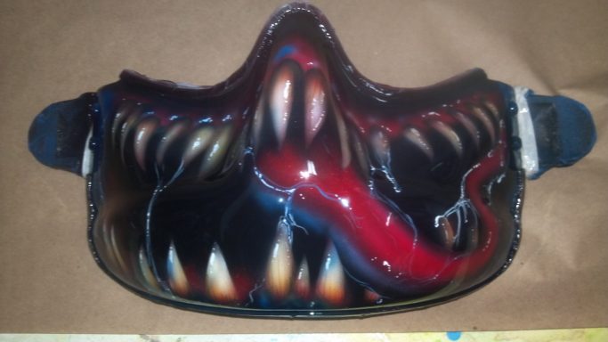 A mask featuring a monstrous design with sharp teeth and a red tongue.