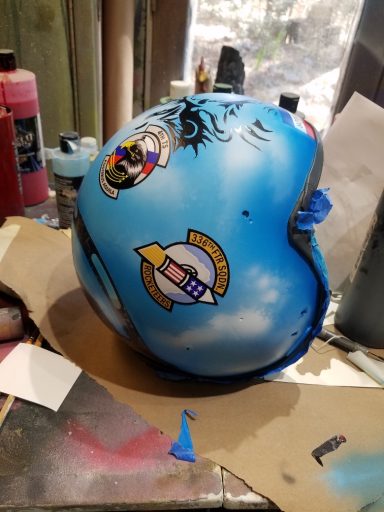 Blue helmet with various colorful stickers and artistic designs on its surface.