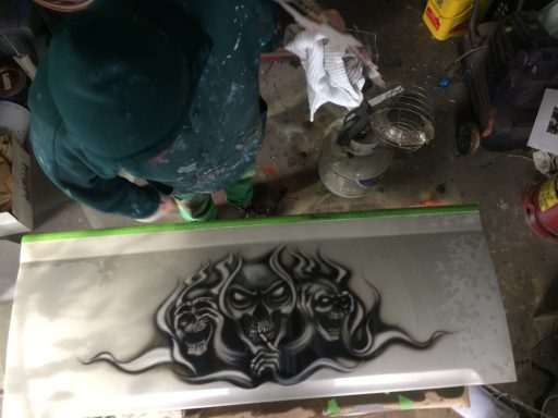 Person working on a textured surface, featuring a large, dark design of three faces.