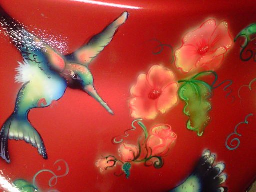 Colorful hummingbirds and flowers painted on a bright red surface.