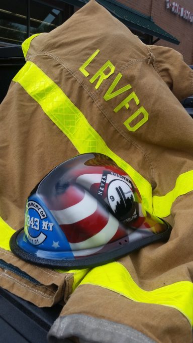 Brown firefighter's jacket with reflective stripes and a helmet featuring American flag design.