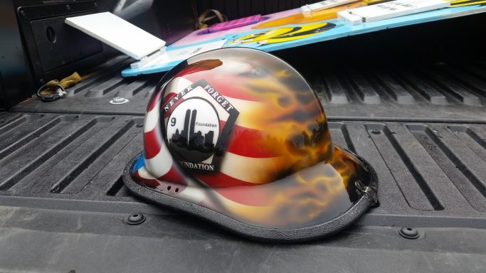 A decorative hard hat with a flame design and a city skyline logo.