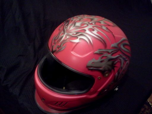 Red motorcycle helmet with tribal designs.