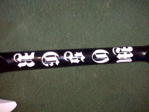 Black baseball bat handle with white symbols and letters printed along the length.