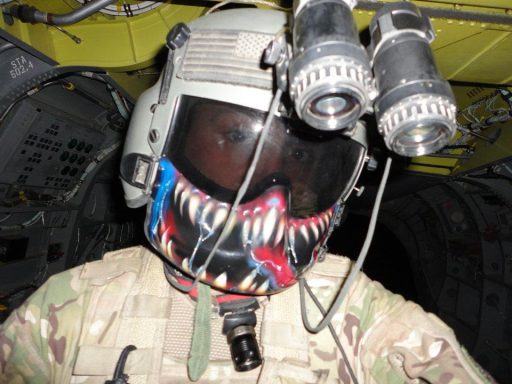 A soldier wearing a tactical helmet with night vision goggles and a colorful mask design.