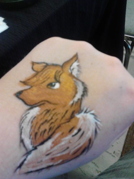 A detailed fox face painted on the back of a hand.