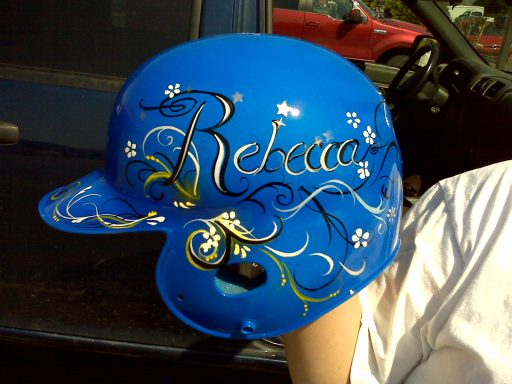 A bright blue helmet with the name "Rebecca" artistically written in decorative script.